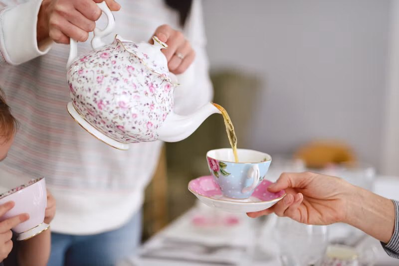 Tea being poured into a cup held out by a friend
